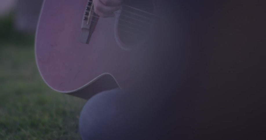 Someone is playing a guitar while sitting on the ground