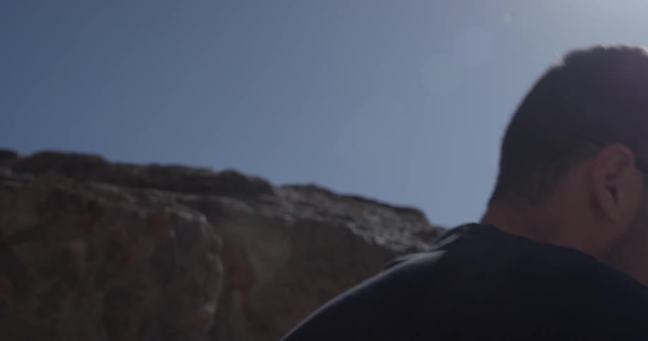 A man wears sunglasses in the desert by rocks