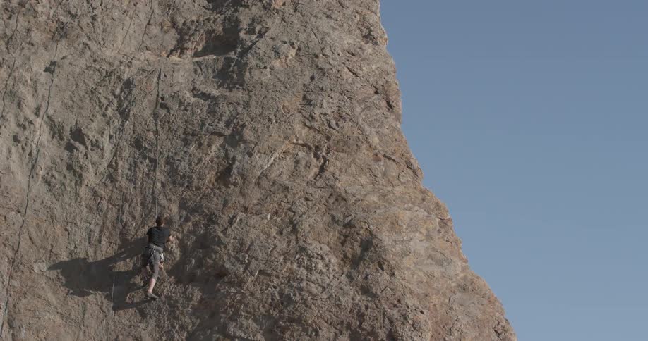 A man climbing a cliff face with a rope