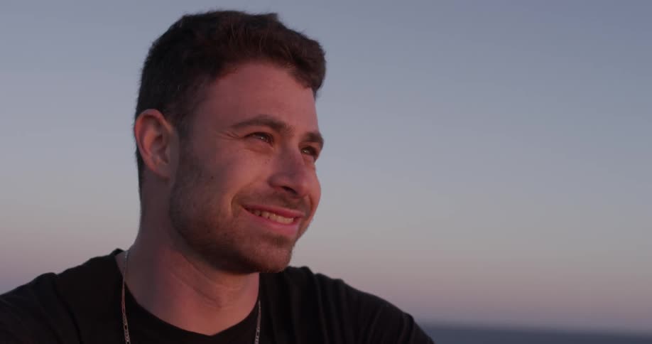 A man smiles while looking into the distance