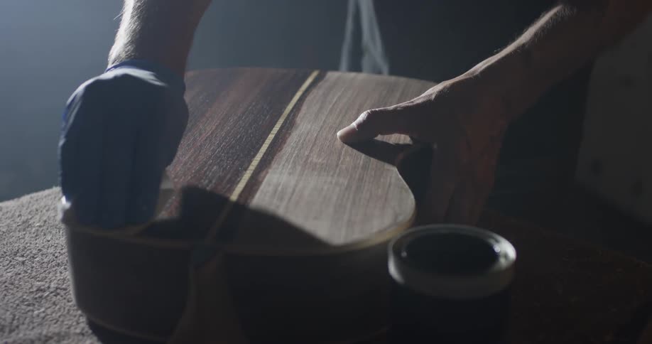 A person putting stain on a guitar