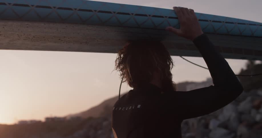 A man carries a surfboard on his head