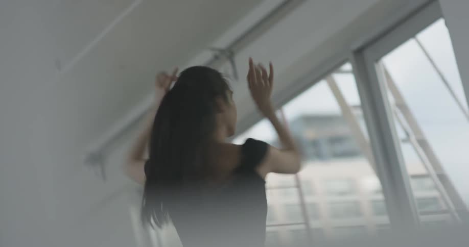 An asian women dances inside a studio alone in the city