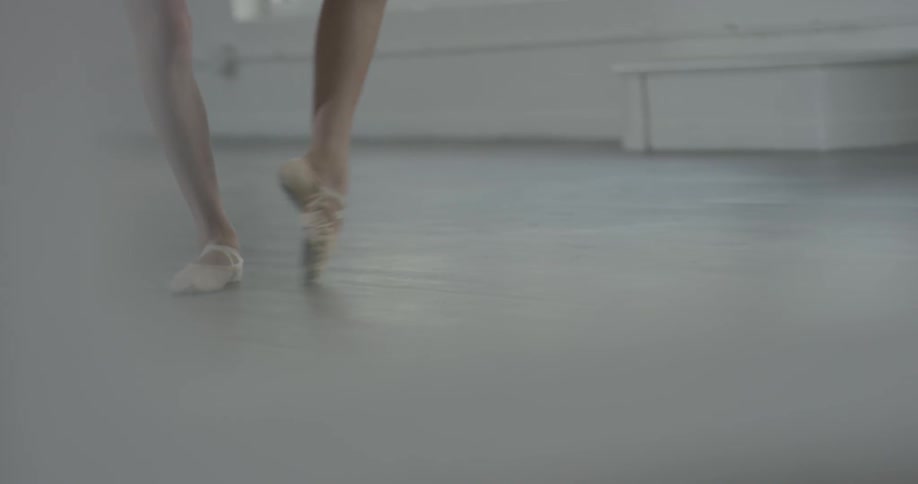 Ballet dancer's legs practicing in white room