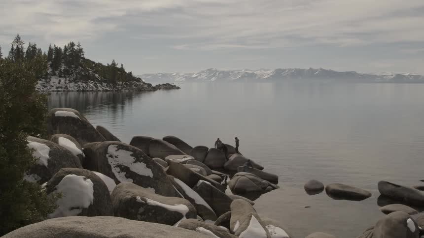A person that is walking on large rocks next to some water