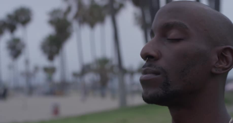 Man meditates on a beach with palm trees