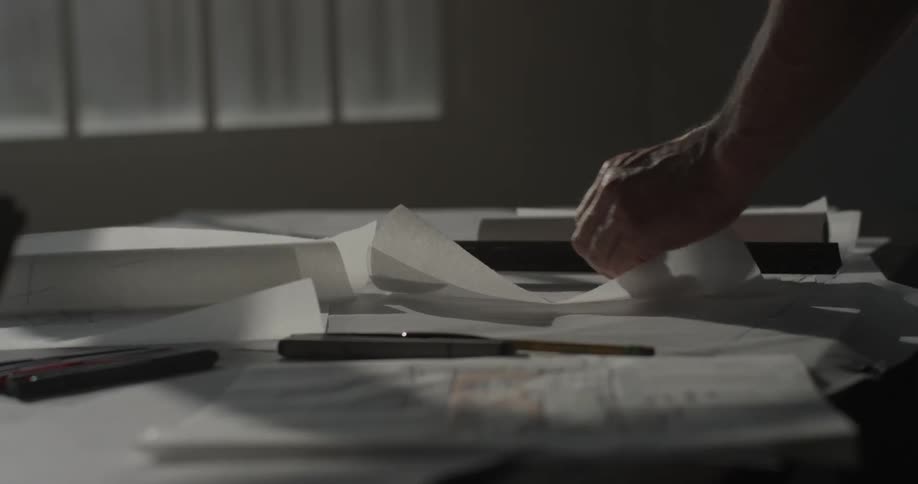 A man that is looking through a piece of paper with a ruler
