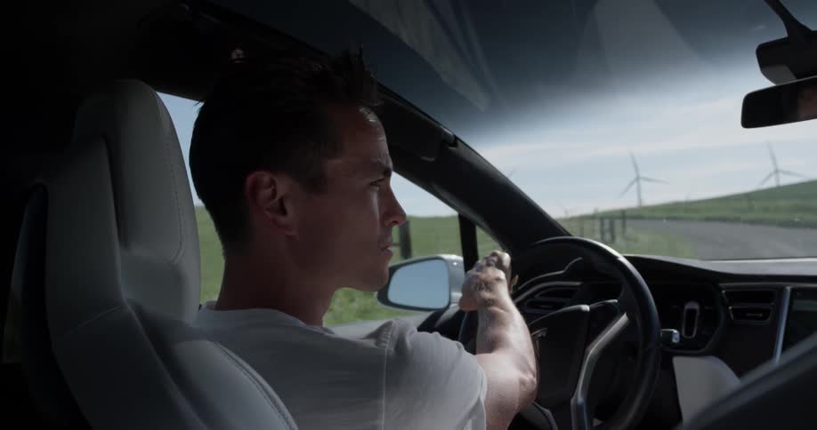 Man driving near a wind farm