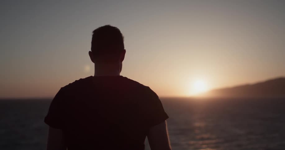 Man looks at sunset on beach