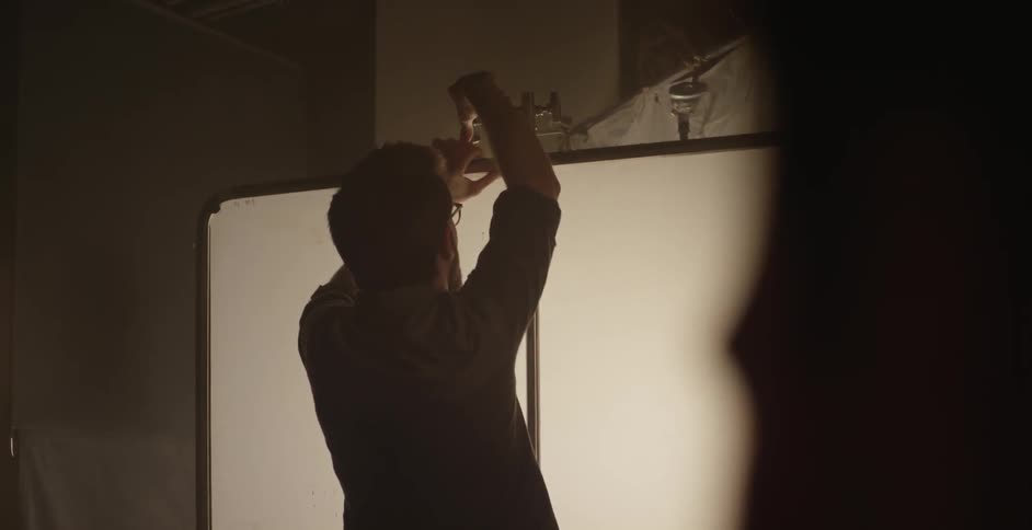 A man hanging a white screen indoors