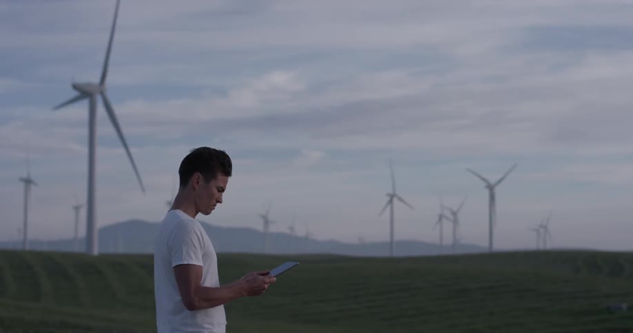 Man Driving Electric Car Through Wind Farm