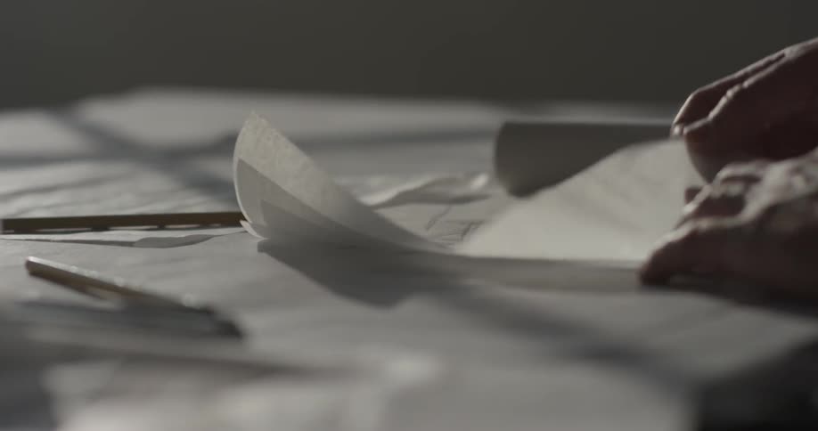 An architect designer flips through papers of different designs on his desk table