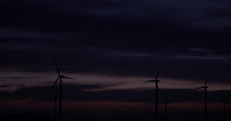 Windmills rotating in a field at night