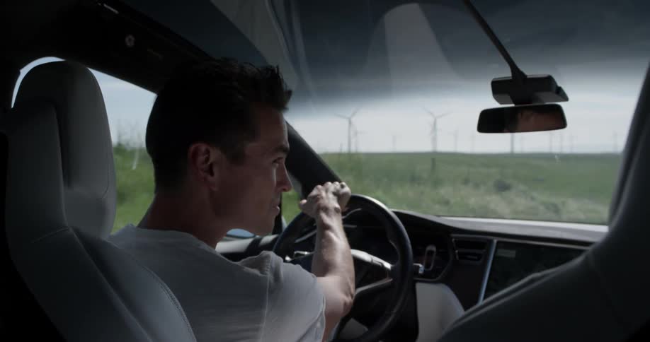 A male driver looks toward the passenger window