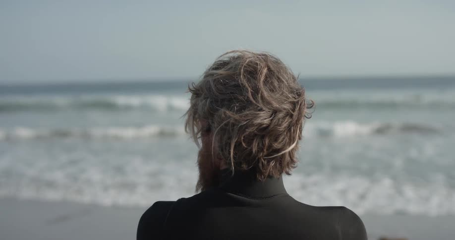 A man in a wetsuit standing next to the ocean