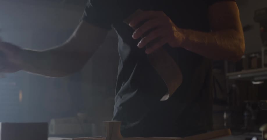 A man spinning a piece of a guitar and attempting to attach it to another piece