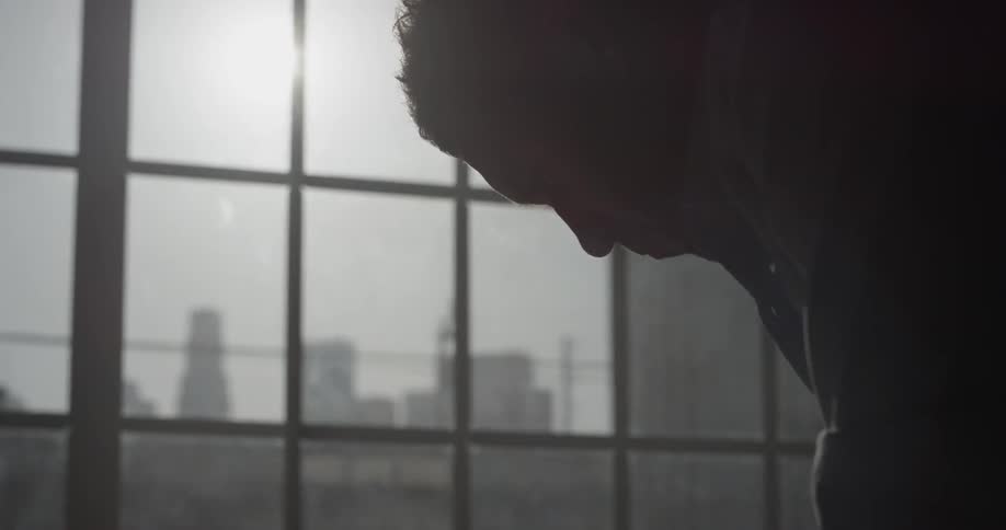 A person that is looking down at a desk in front of a window
