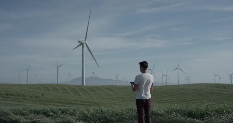 Man Driving Electric Car Through Wind Farm