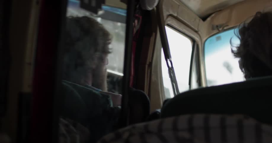 Mirror in a car shows a guy driving while trees pass by
