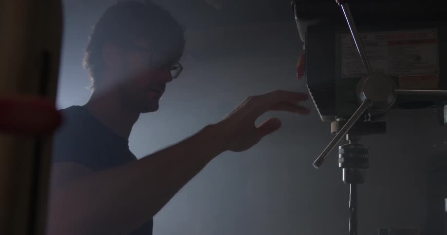A man using a large drill to make a hole and blows the dust away