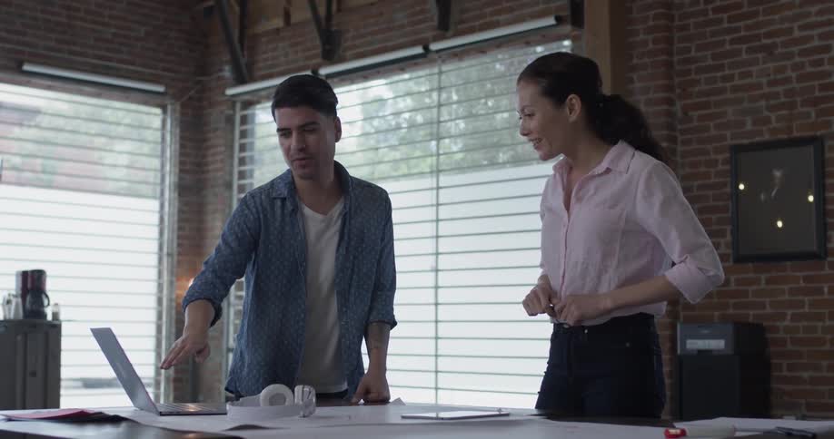 A man explains to a woman what is on the screen of a laptop