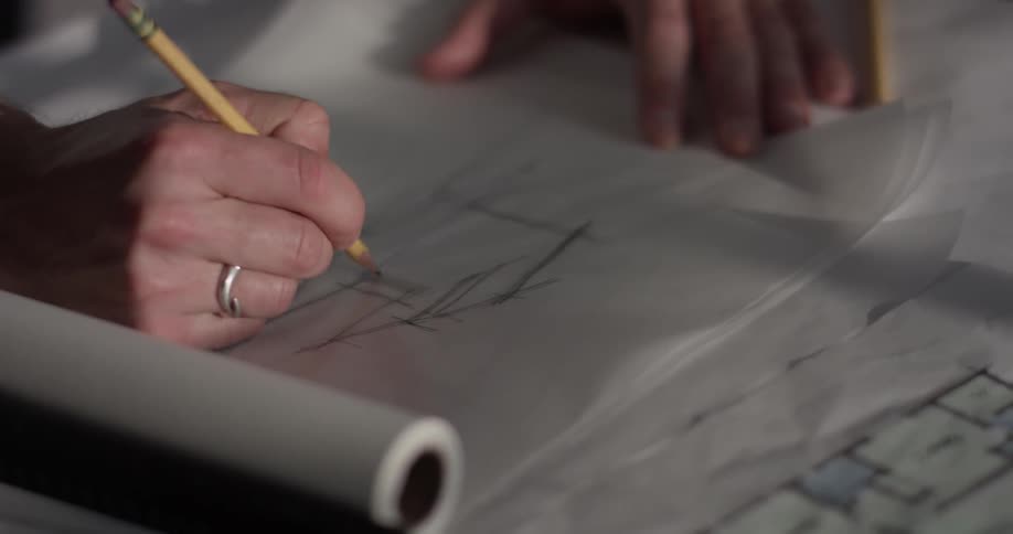 A person sketching a house with a pencil