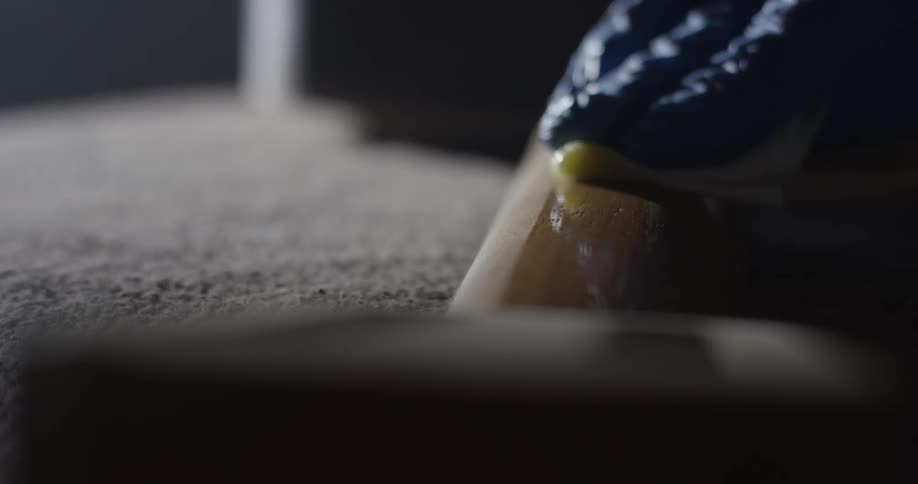 A gloved hand using a sponge to wipe a liquid