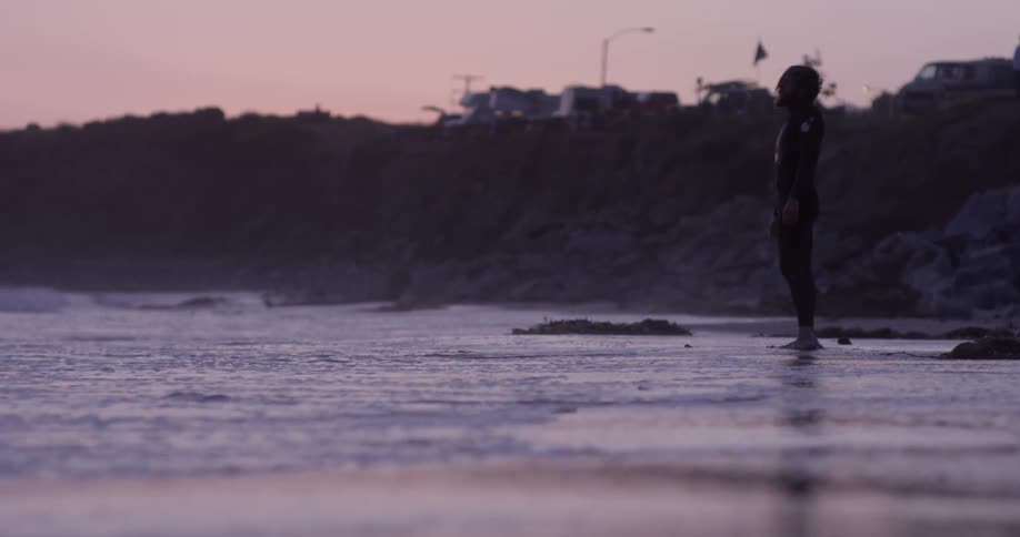 Man stands on the beach at sunset