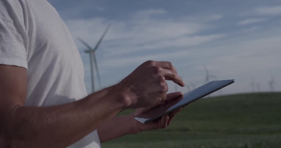 A man tapping the screen of a tablet out in a field