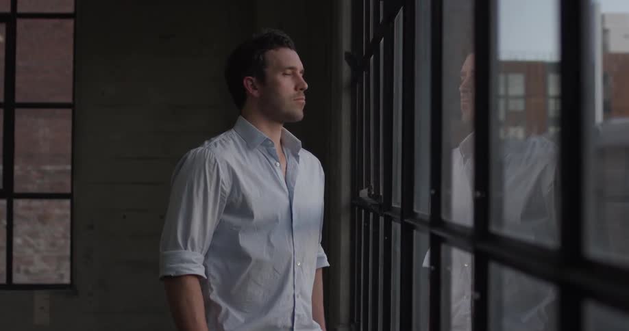 A man looking out a window and thinking