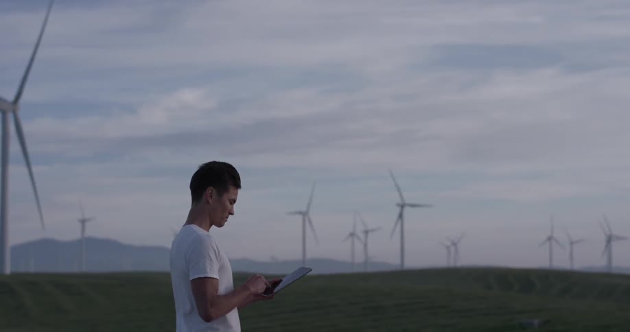 A man uses a tablet near windmills