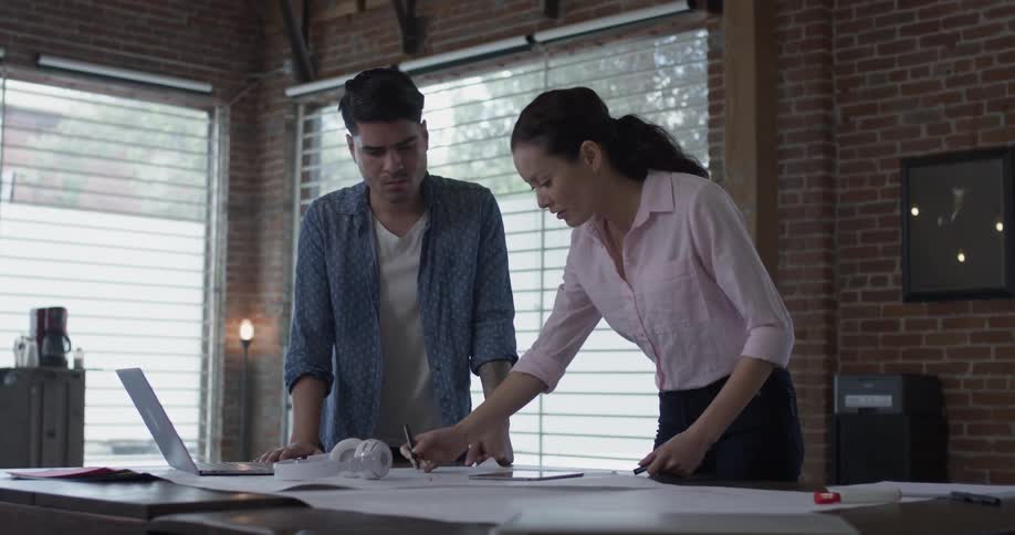 Two people discussing what they are working on in an office