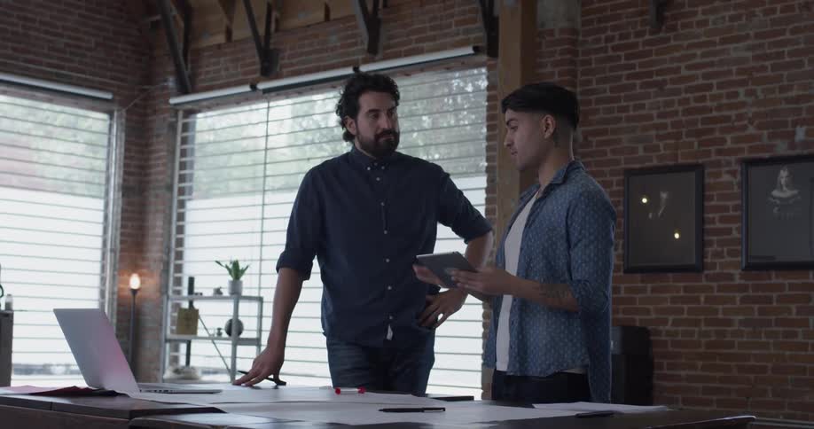 Two men talking about an item on a tablet