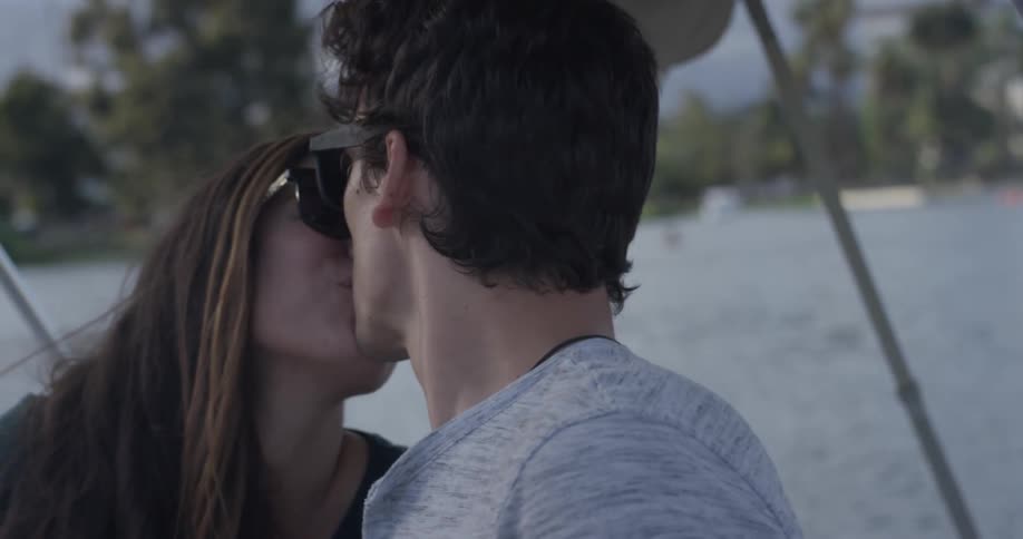 A man and a woman kissing in a boat on a lake