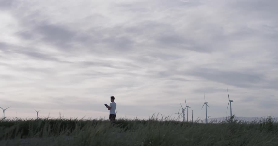 Man Driving Electric Car Through Wind Farm