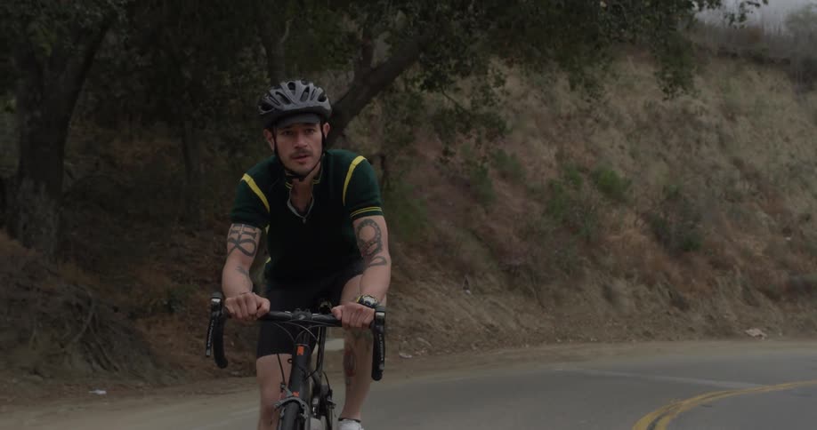 A man rides a mountain bike down a road surrounded by trees