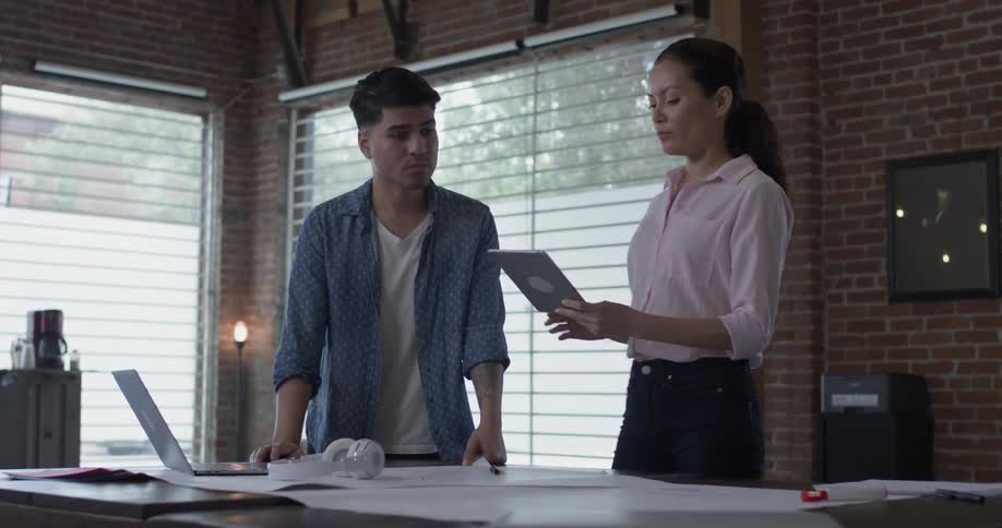 A woman is sketching something and shows the man beside her what she has done