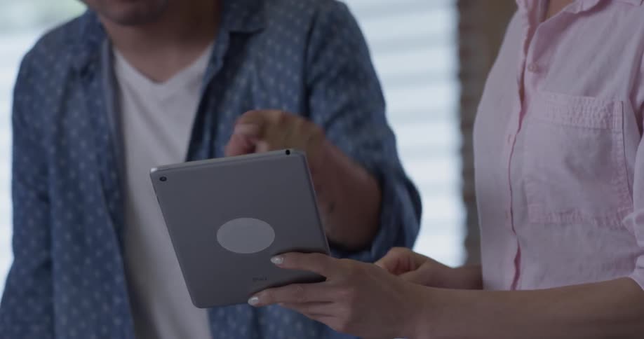 A man nods his head toward a woman holding a tablet