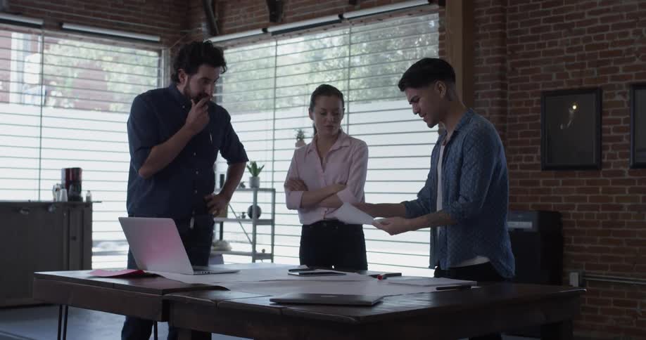 Two men and one woman looking at things on a piece of paper