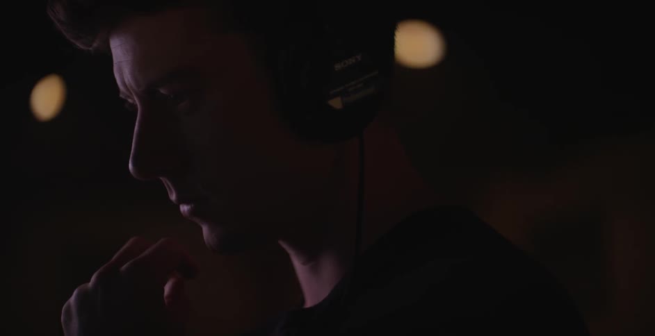 A man wearing headphones appears to be concentrating