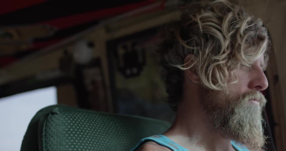 Man with a beard stares ahead while driving a van