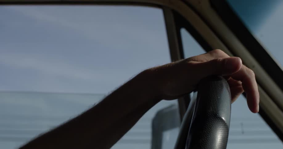 A person driving a car along the side of the ocean