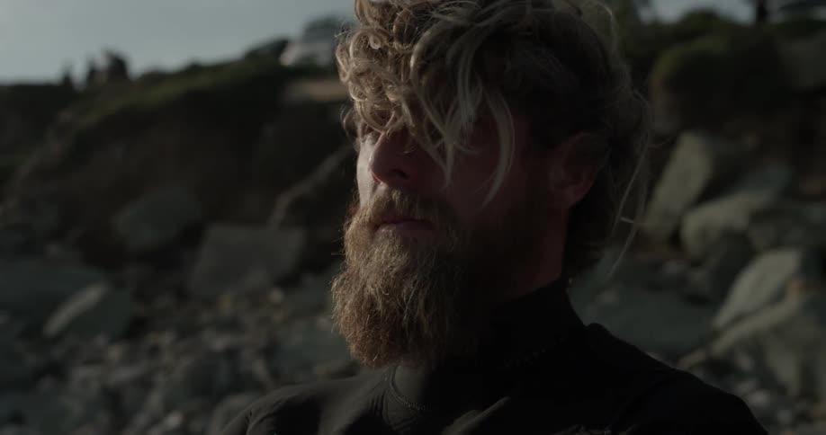 A man in a wetsuit looking at the sea