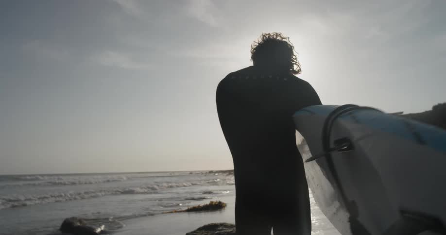 A person stepping out into the ocean with a surfboard