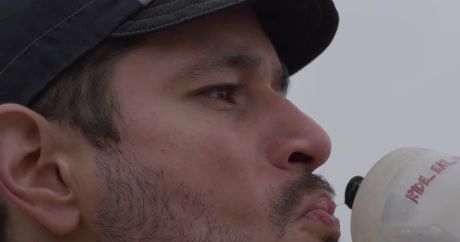 A man is drinking water outside