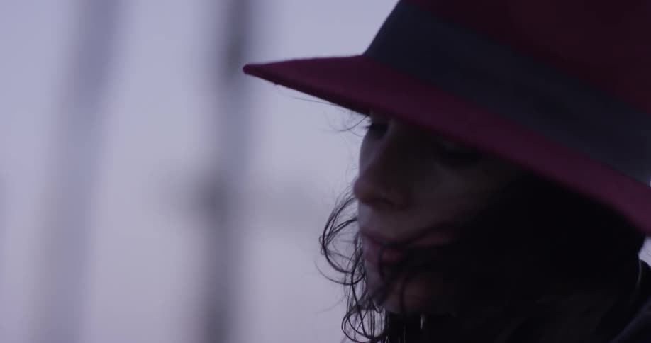A woman wearing a hat has wind blowing through her hair