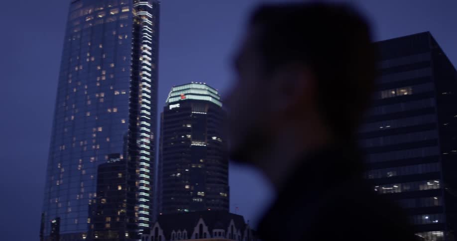 Someone stands looking at skyscrapers in the twilight