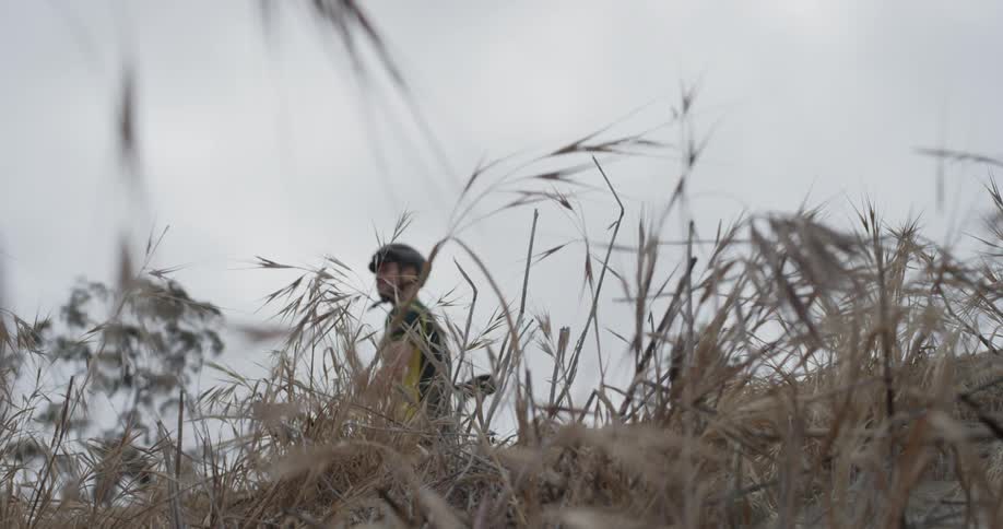 A man walking their bike through a field