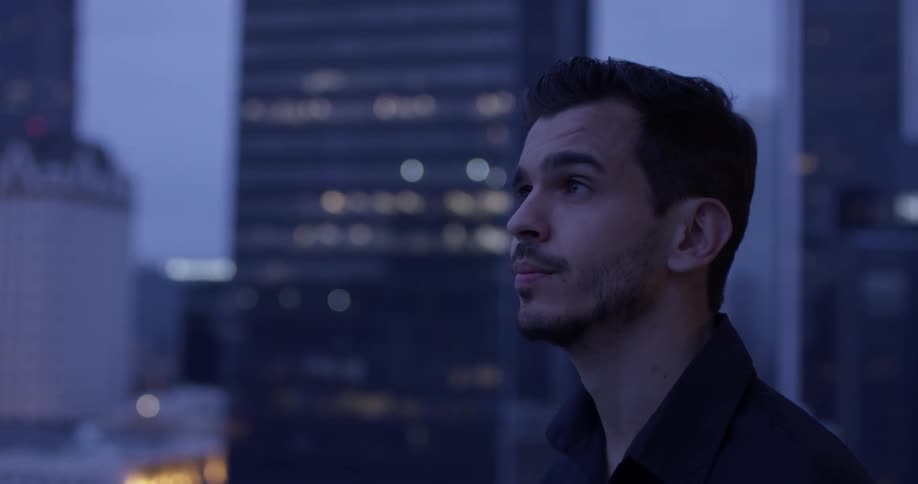 A man standing on a rooftop looking at a city