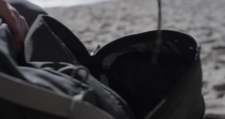 A person that is getting a pair of shoes out of a backpack